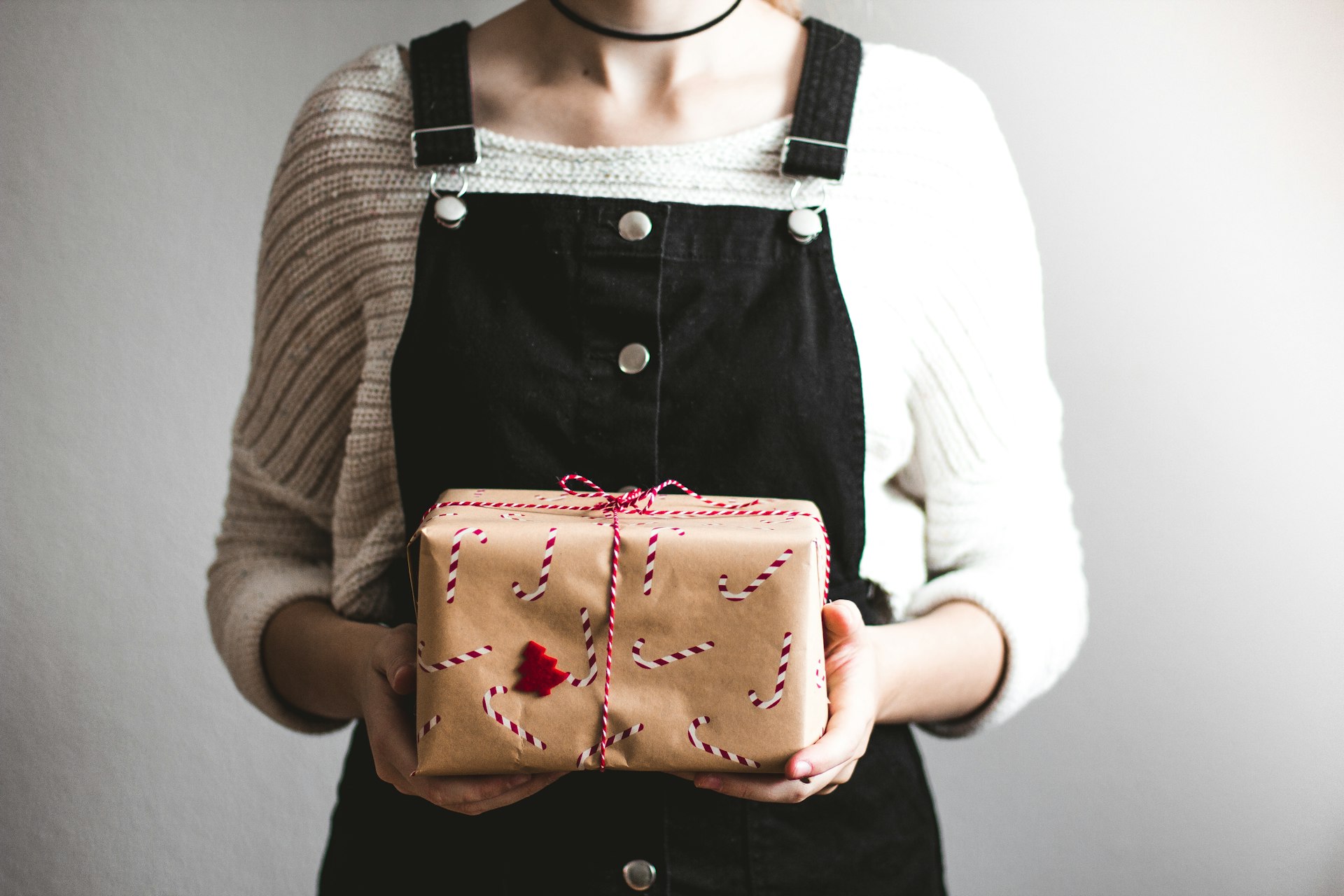 woman holding brown gift box standing in front of white wall